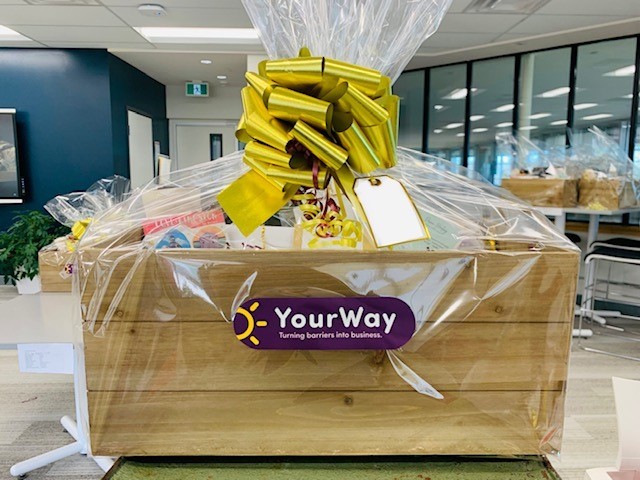 A gift basket wrapped in cellophane shows the YourWay logo